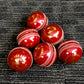 Pack of 6 red cricket balls, 'Black Ash Cavalier' series, made from premium quality, genuine Australian alum-tanned leather with 4-piece construction. These waterproof, machine-stitched balls offer excellent shape retention, are suitable for 50 overs, comply with MCC regulations, and weigh 156 grams (5.5 ounces) each.