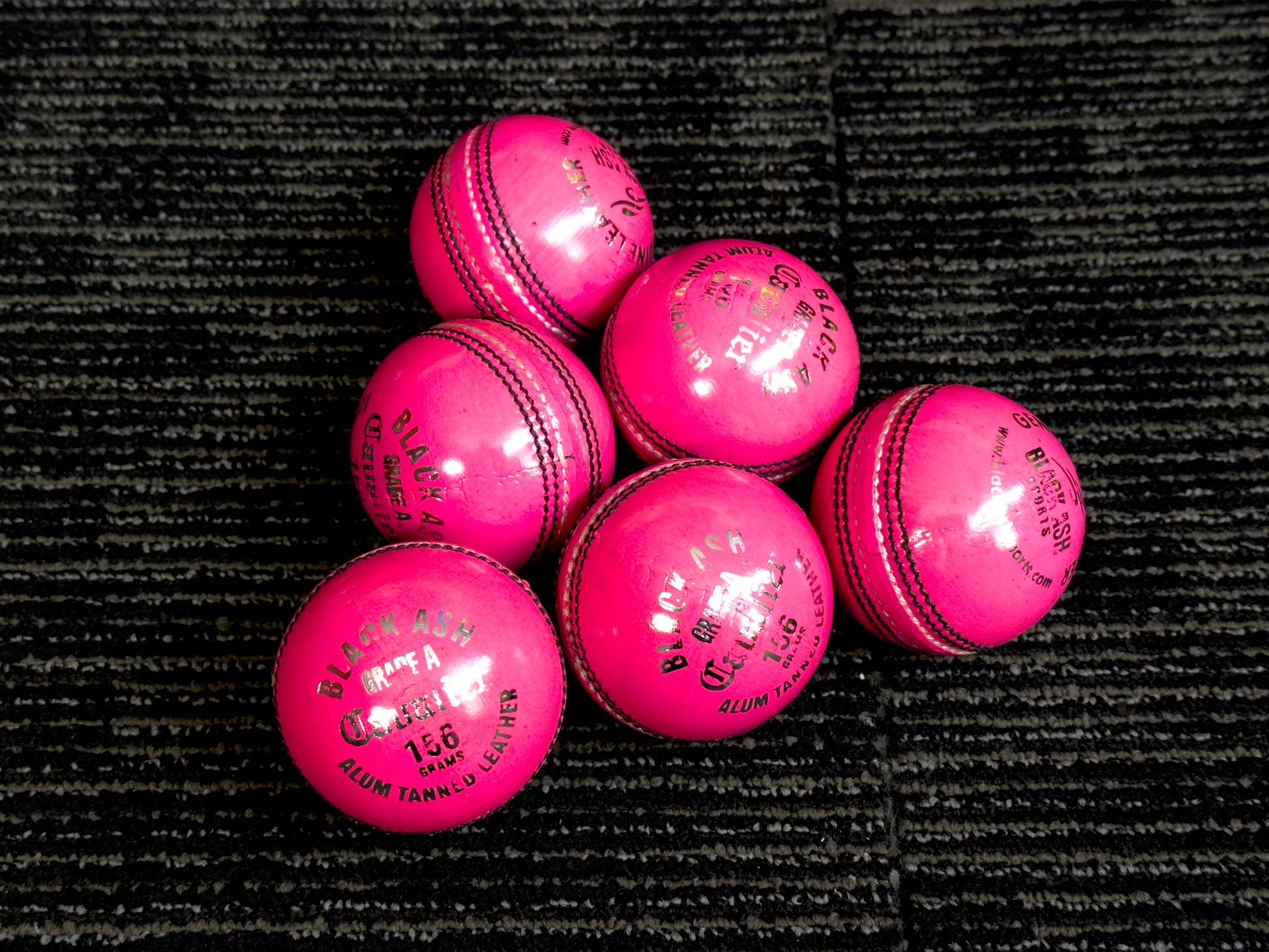 Pack of 6 pink cricket balls named 'Black Ash Cavalier,' crafted from premium quality, genuine Australian alum-tanned leather with a 4-piece construction for superior shape retention. These waterproof balls are suitable for 50 overs, conform to MCC regulations, machine-stitched, and each weighs 156 grams (5.5 ounces).
