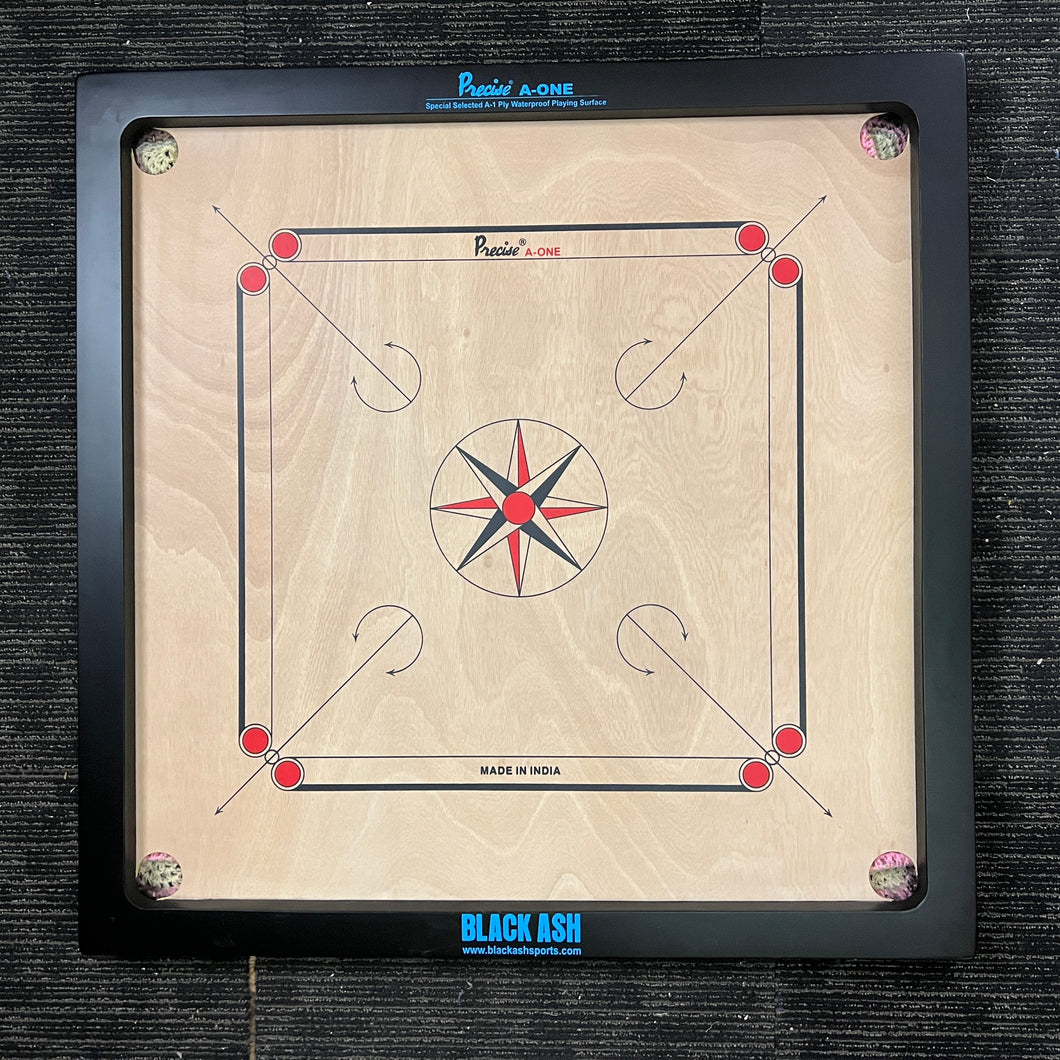 PRECISE Excel A-One carrom board with a 6mm thick special selected A-One waterproof ply, measuring 32x32 inches overall with a 29x29 inch playing area, 1.5-inch borders, and strong hand-knitted wool nets. Includes a striker and a set of coins, featuring plastic feet for elevation.