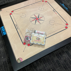 PRECISE Excel A-One carrom board with a 6mm thick special selected A-One waterproof ply, measuring 32x32 inches overall with a 29x29 inch playing area, 1.5-inch borders, and strong hand-knitted wool nets. Includes a striker and a set of coins, featuring plastic feet for elevation.