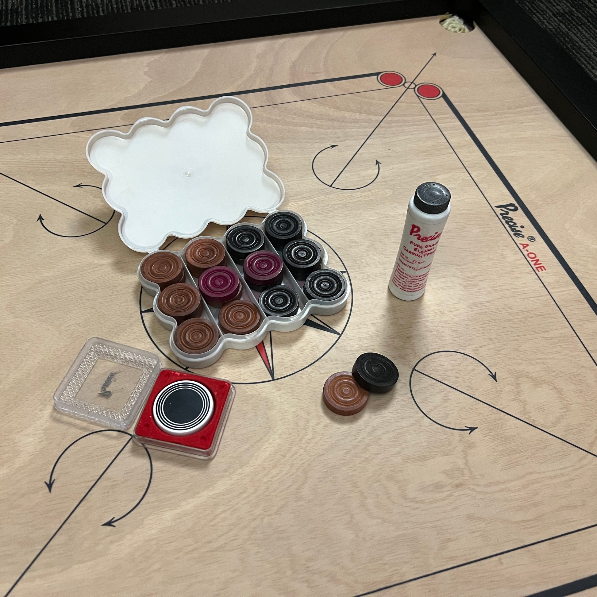 PRECISE Excel A-One carrom board with a 6mm thick special selected A-One waterproof ply, measuring 32x32 inches overall with a 29x29 inch playing area, 1.5-inch borders, and strong hand-knitted wool nets. Includes a striker and a set of coins, featuring plastic feet for elevation.