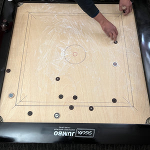 Black Ash 'Jumbo' high-end special edition carrom board by SISCAA, made of English Birchwood, 51x51 inches with a 41x41 inch playing area, 12mm sheet thickness, and 5-inch borders. Includes premium finish, fast rebound borders, heavy-duty back support, high-end coins, and 2 strikers.